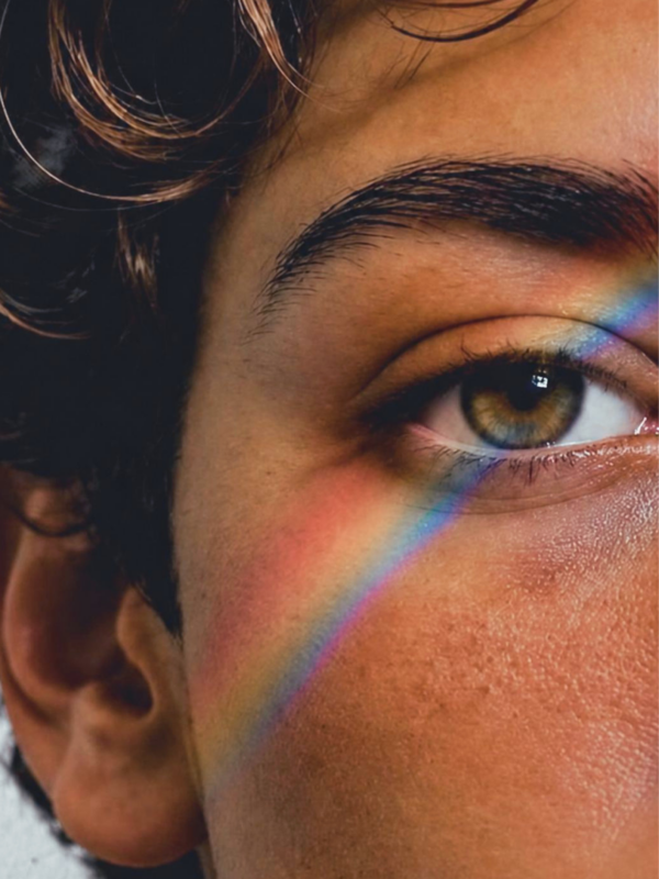 Gezicht zonder duidelijk gender met regenboogreflectie — diversiteit, inclusiviteit en genderzorg